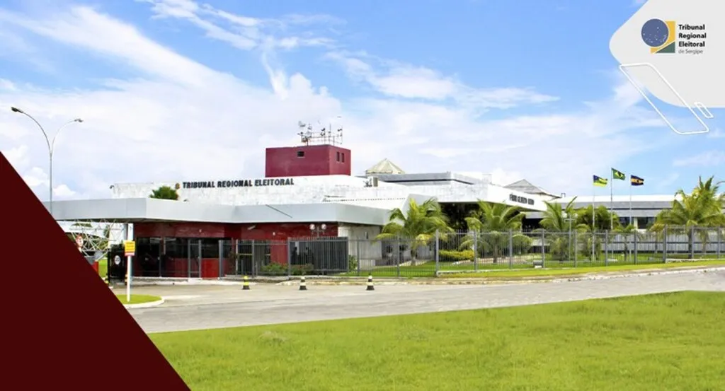 Prédio do Tribunal Regional Eleitoral de Sergipe, fachada moderna com muros baixos, grades e palmeiras ao redor.